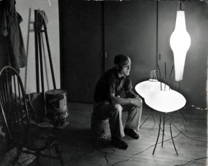 Isamu Noguchi seated with three Akari, c. 1950s. Image Courtesy of The Noguchi Museum